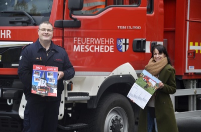 Hans-Jrg Steiner (Freiwillige Feuerwehr der Stadt Meschede) und Steffi Kroggel (Stadtmarketing Meschede) prsentieren den Feuerwehrkalender 2021. Bildnachweis: Stadtmarketing Meschede